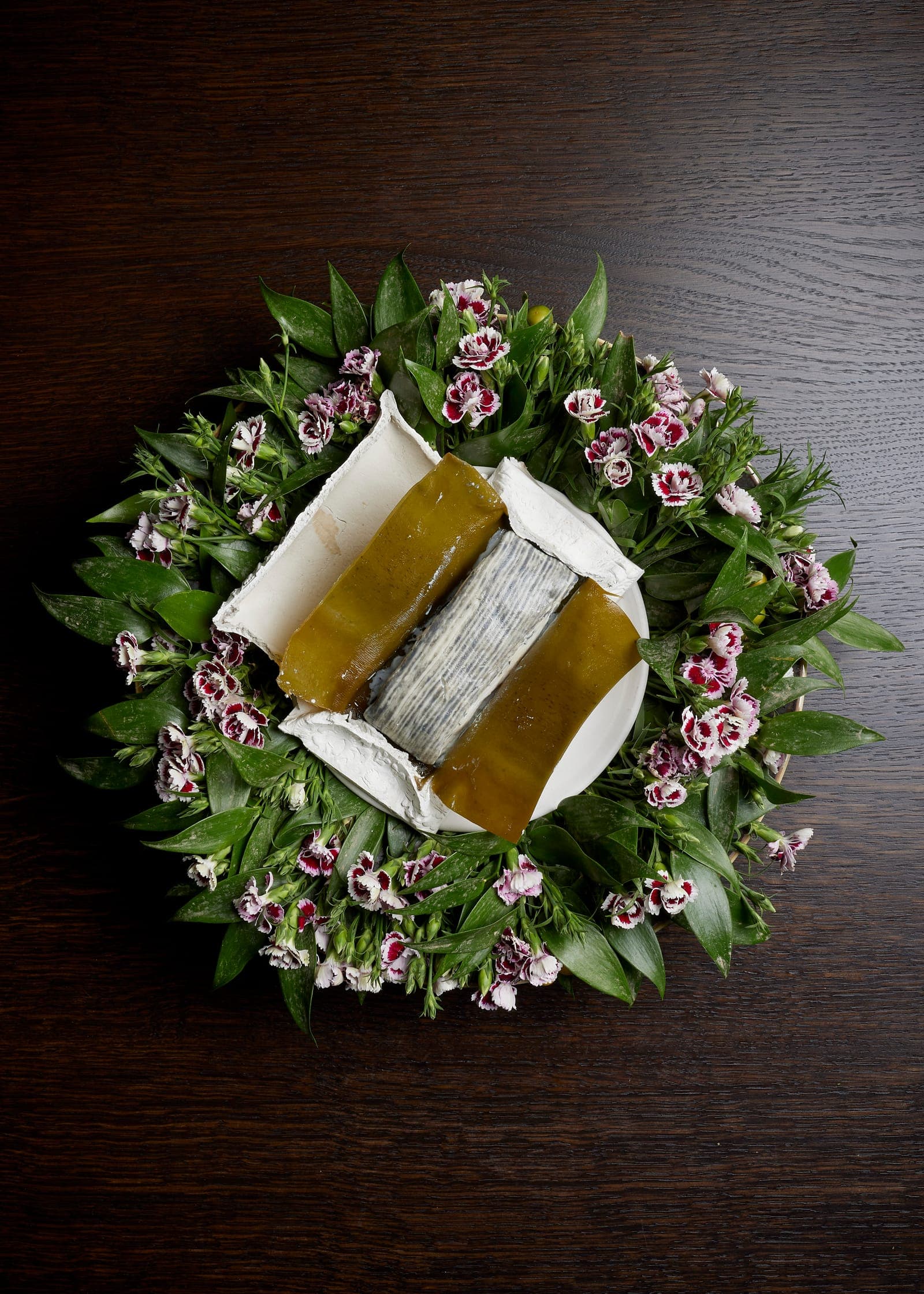A dessert in a ring of fresh flowers and leaves, seen from above